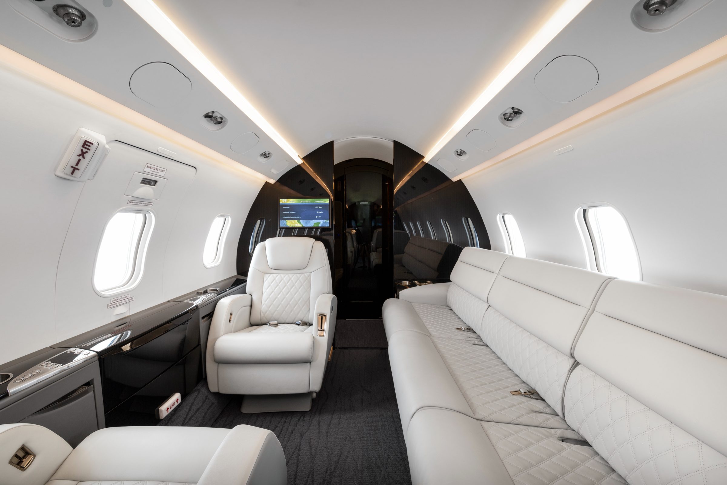 Aft cabin with a long quilted divan and forward-facing seat, Airshow moving map on the bulkhead monitor